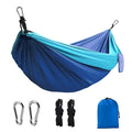 Blue nylon parachute cloth camping hammock hung between two trees outdoors
