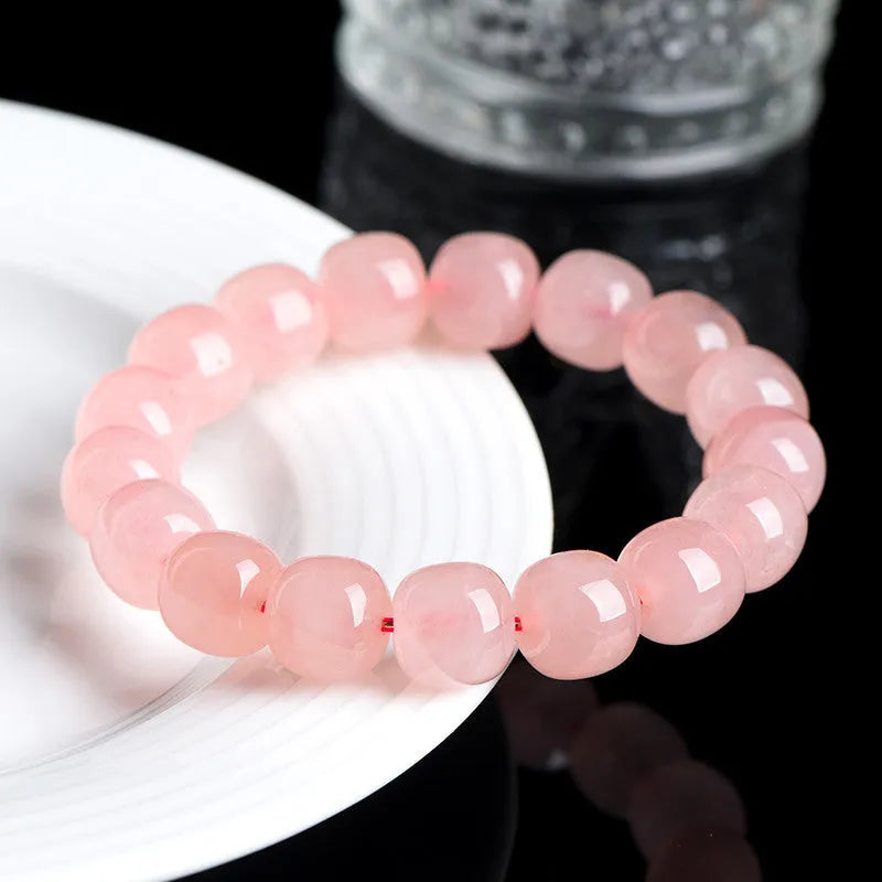 Close-up of a pink natural crystal barrel bead bracelet with geometric beads on a wrist.