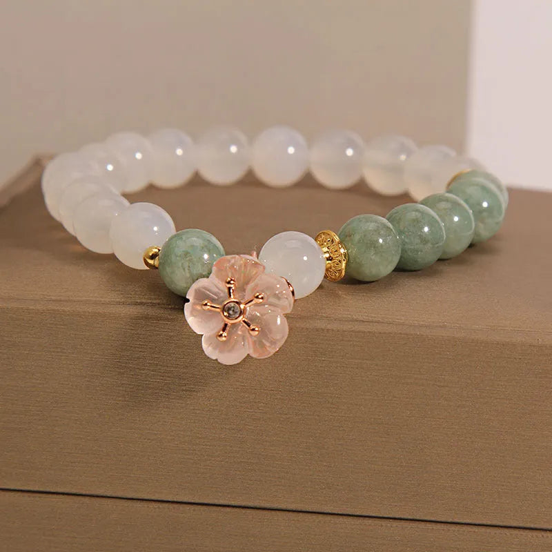 Women's white agate jade flower bracelet on a wrist, showing detailed floral carving.