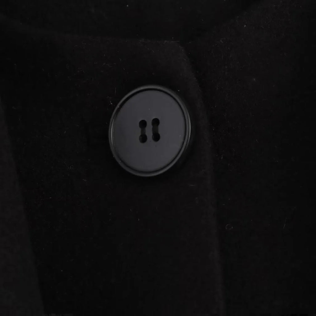 Women's long black overcoat with a grey fur collar and pockets, shown on a model.