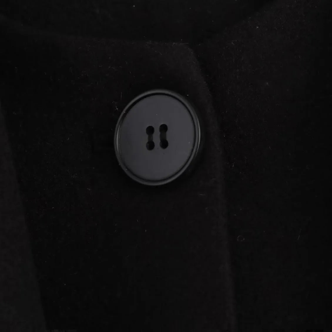 Women's long black overcoat with a grey fur collar and pockets, shown on a model.