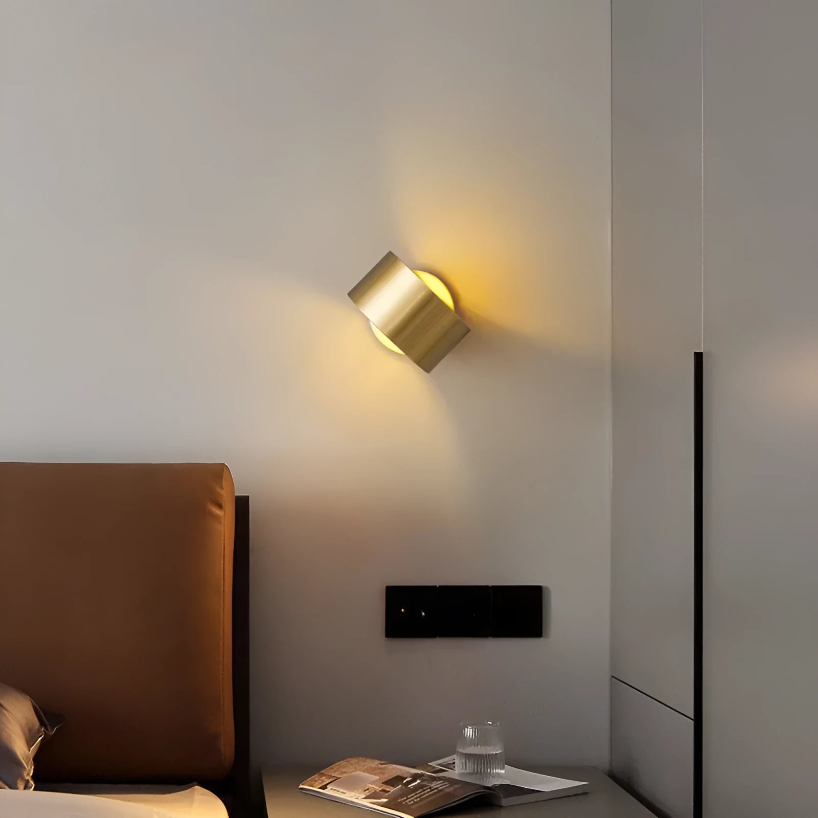 A modern simple style copper wall lamp in a gold finish, mounted on a wall.