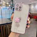 Green iPhone case with a 3D white flower spin stand on the back, showing the built-in screen protector.