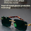 Frameless dark green crystal sunglasses with a glasses case and cleaning cloth.