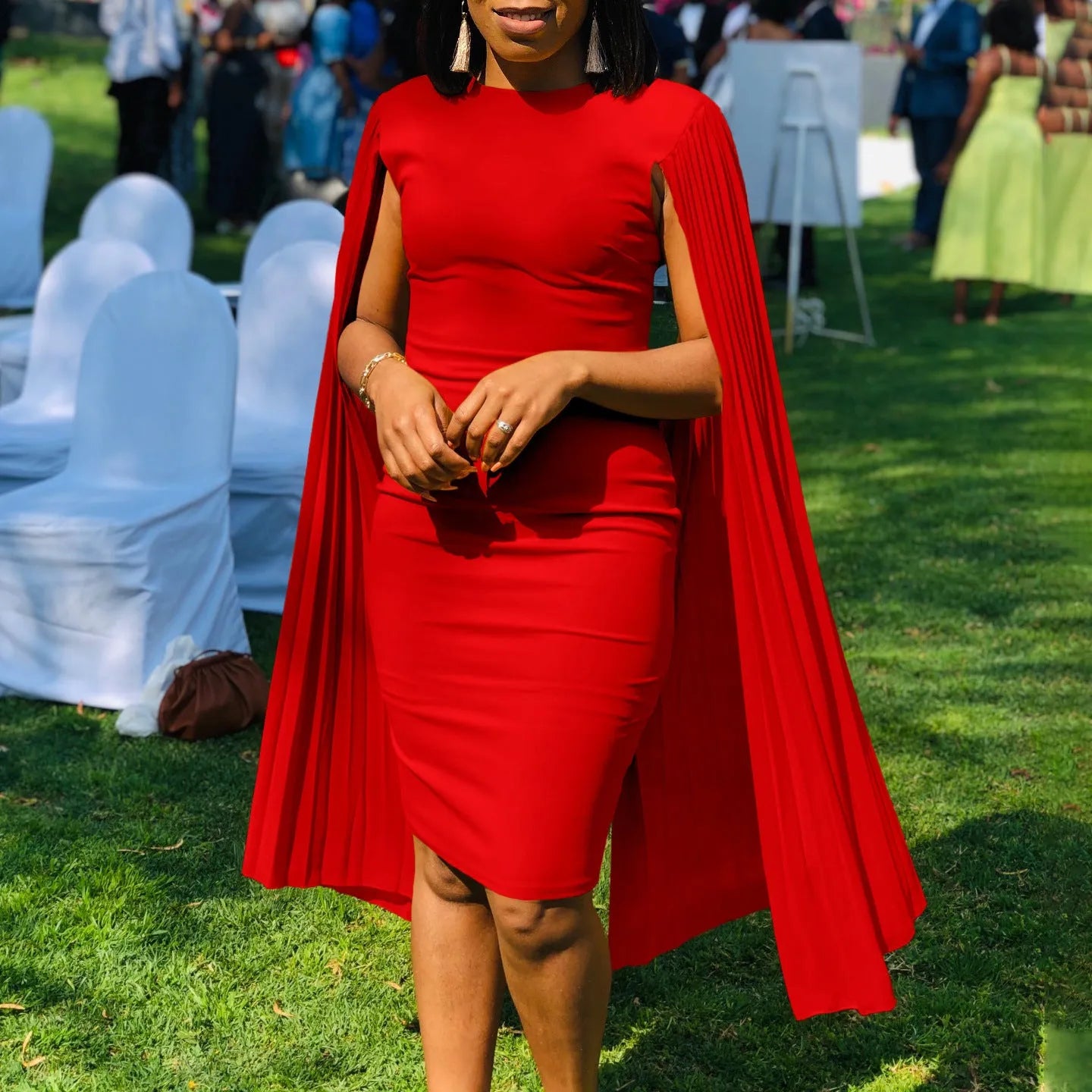 A woman wearing a long sleeve, high-waisted pleated evening gown in a formal setting.