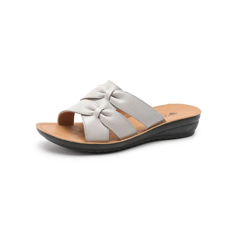 Beige cowhide leather slippers for women with a soft sole, shown from the side.