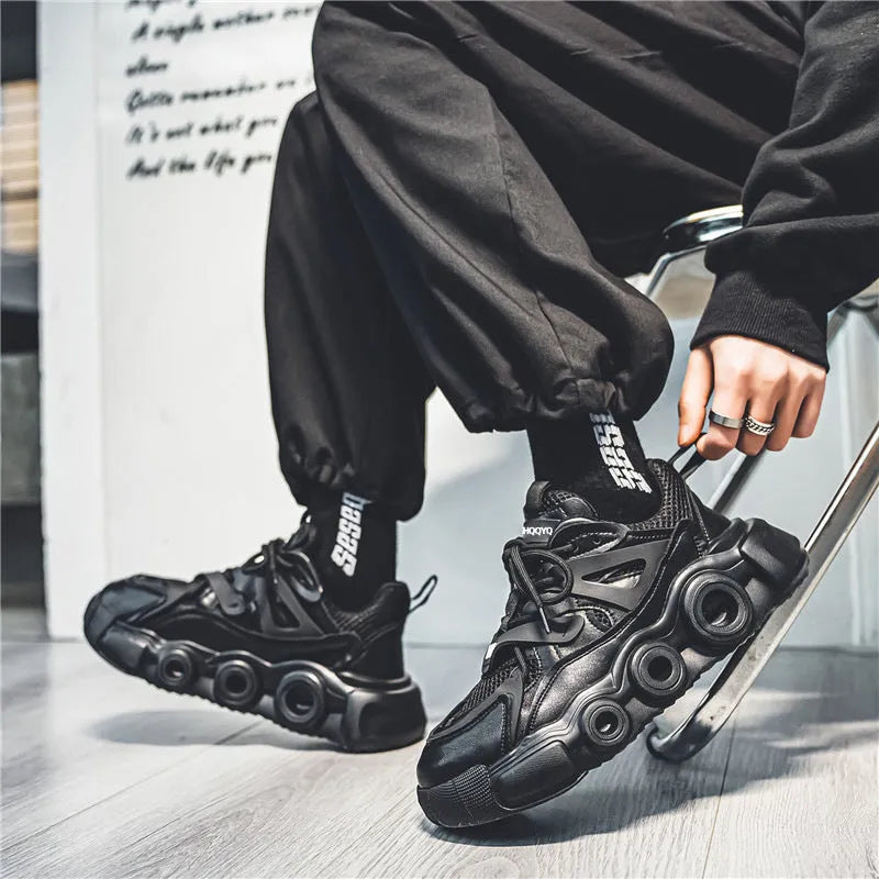 Men's black low-top sneakers with mesh upper, thick rubber sole, and round toe lace-up design.