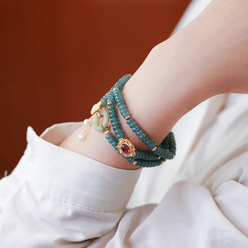 Close-up of a women's blue water jade abacus bead bracelet with three rings, tourmaline, and pearl accents.