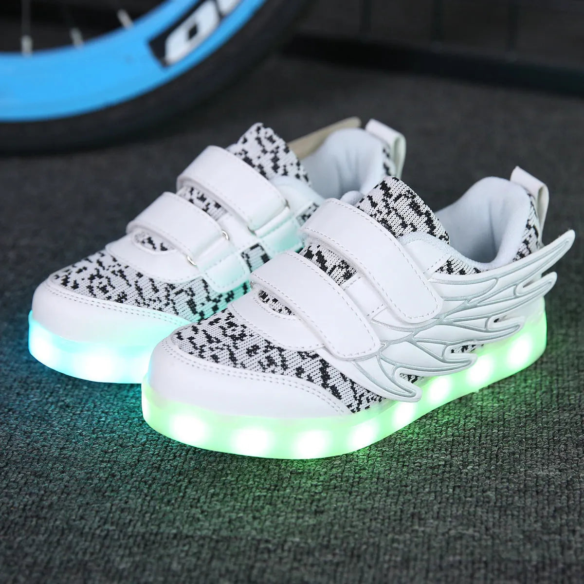 Children's plum red and white LED light-up sneakers showing USB charging port and colourful illumination.