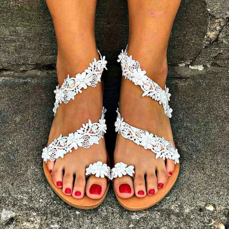 White women's sandals with rhinestone floral decoration on PU upper, slip-on flat design.