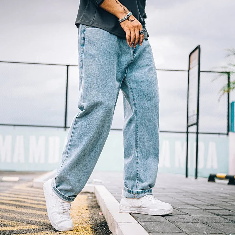 Men's dark blue loose straight-leg casual jeans on a hanger, showing mid-waist and zipper fly.