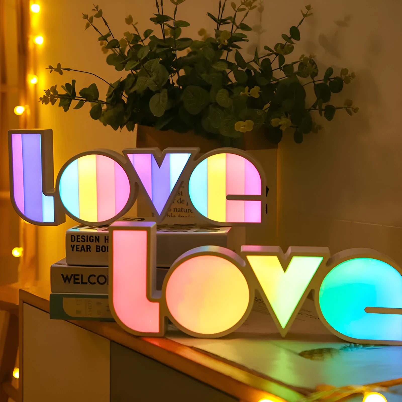 Rainbow style plastic LED decorative light spelling LOVE, shown on a table.