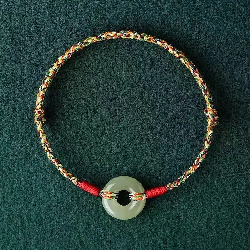 A woven bracelet with a peace buckle on a colourful braided rope.
