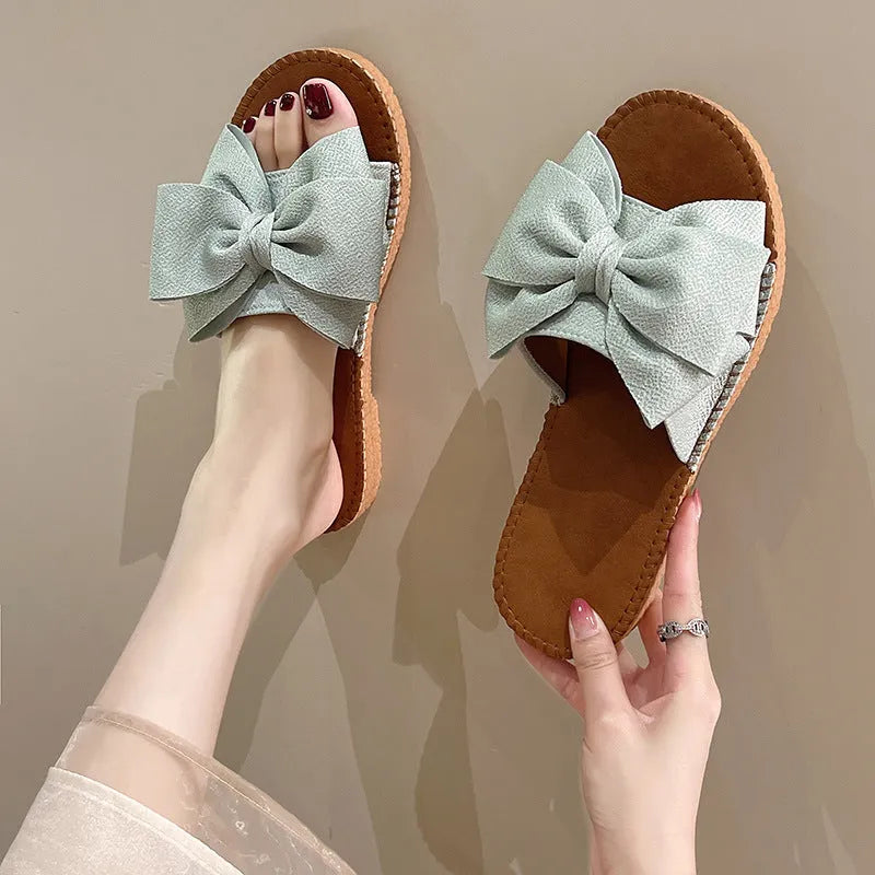 Women's slip-on cloth sandals with bow detail in beige, light green, and pink colours