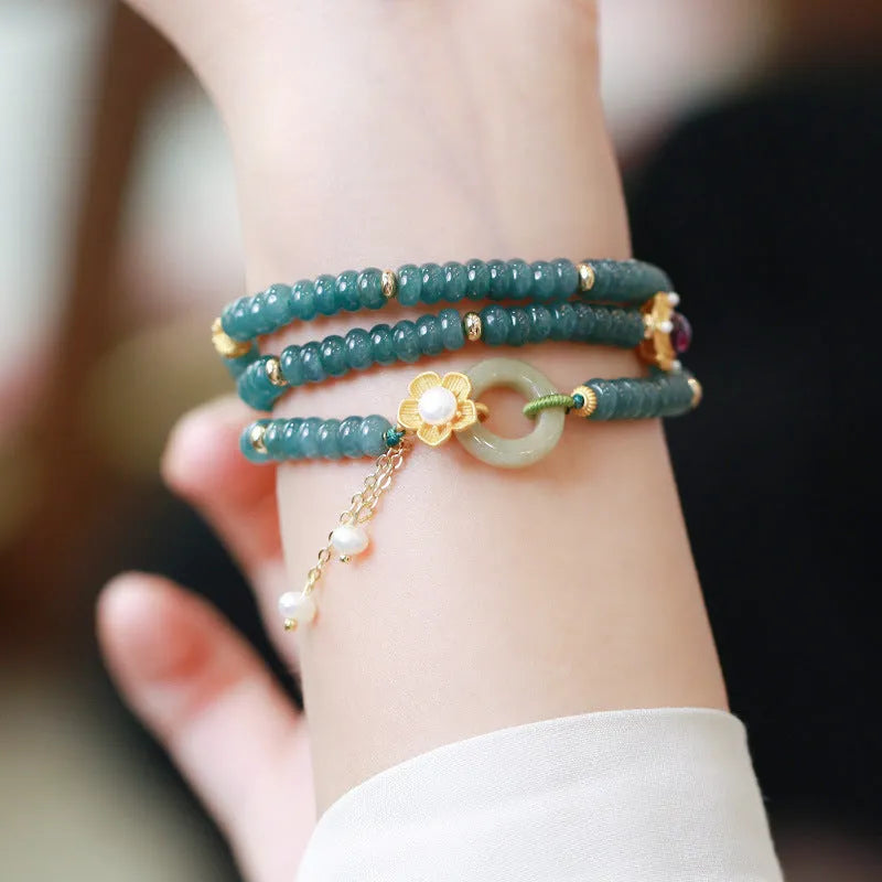 Close-up of a women's blue water jade abacus bead bracelet with three rings, tourmaline, and pearl accents.