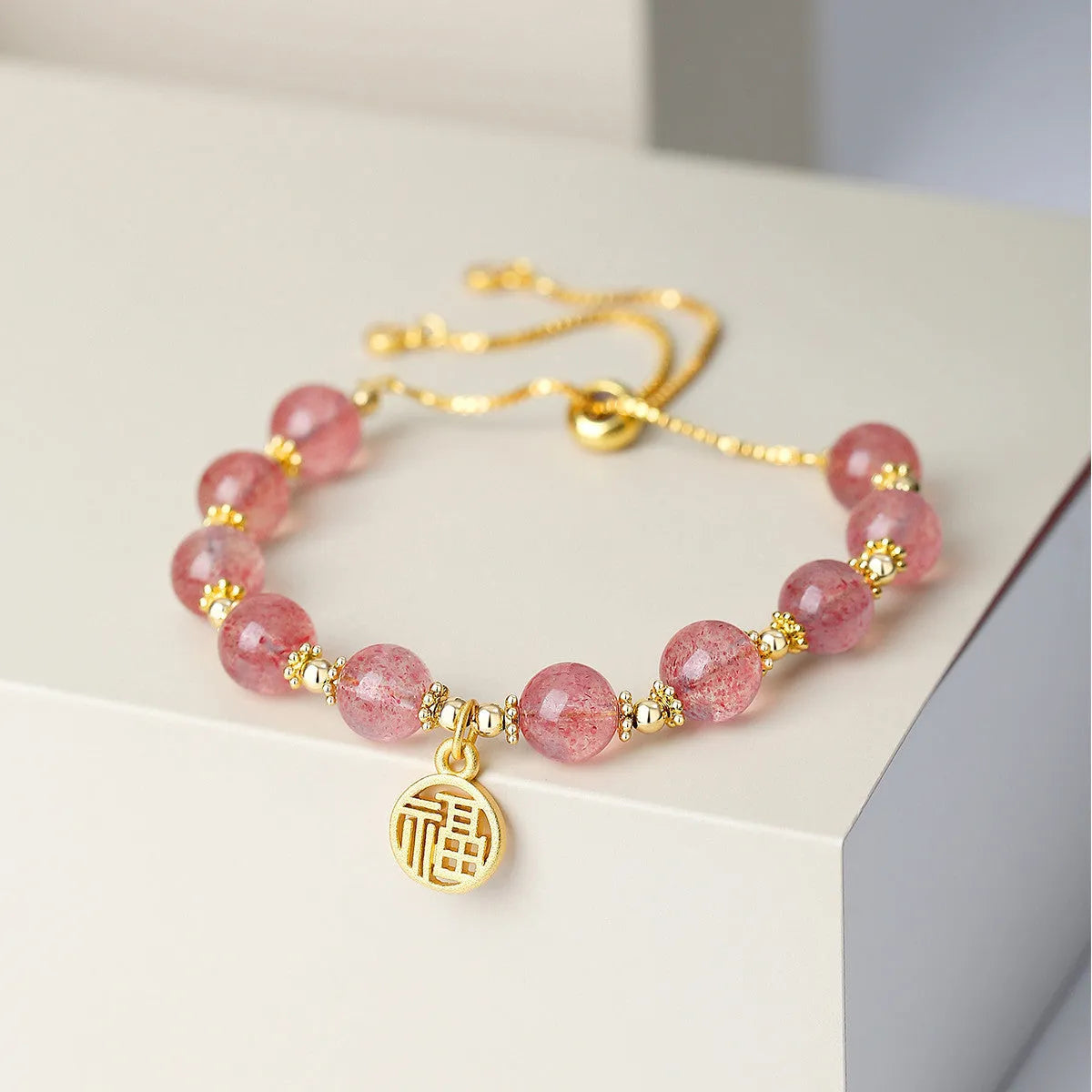 Women's strawberry quartz crystal bracelet with electroplated fu character charm and geometric design