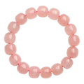 Close-up of a pink natural crystal barrel bead bracelet with geometric beads on a wrist.