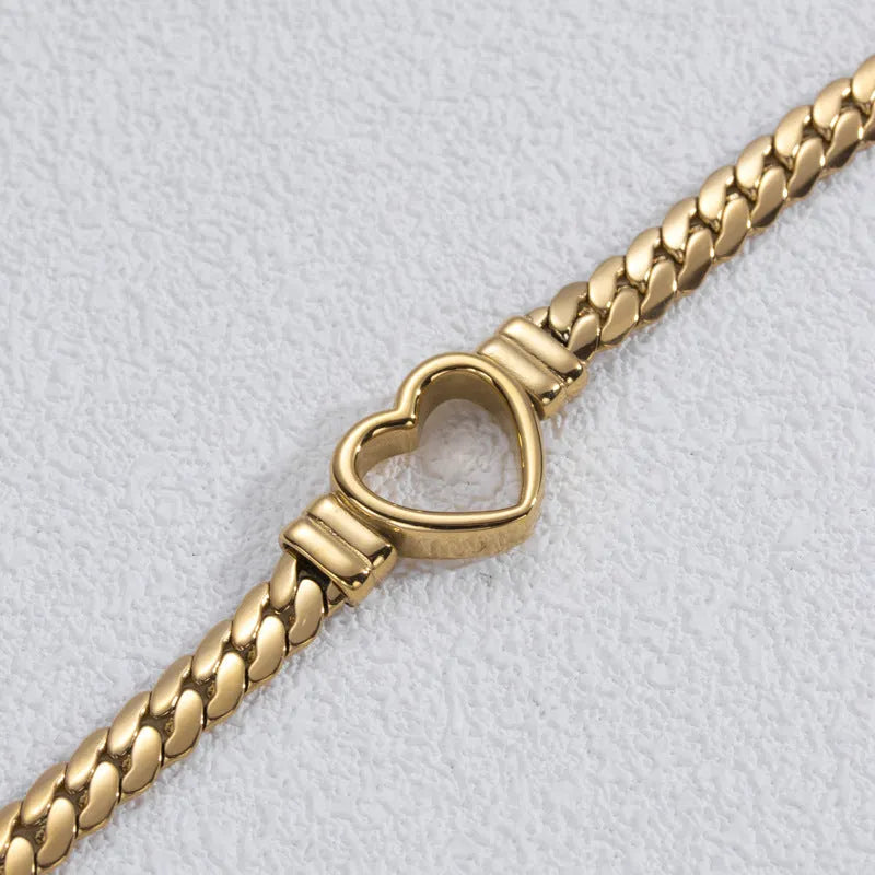Fashion simple hollow heart titanium steel bracelet in BR-26 gold finish on a neutral background