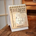 Small 2025 mini desk calendar open to a daily page, showing modern simple design on a desk.