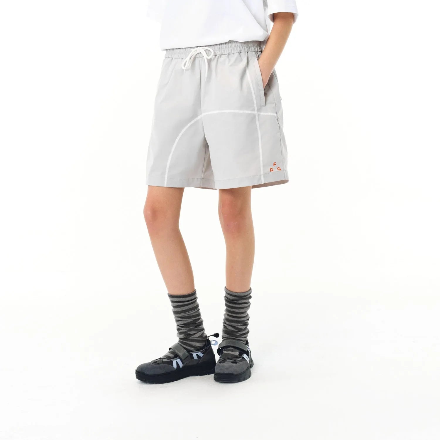 High-elasticity polyester drawstring shorts in apricot colour on a beach background.