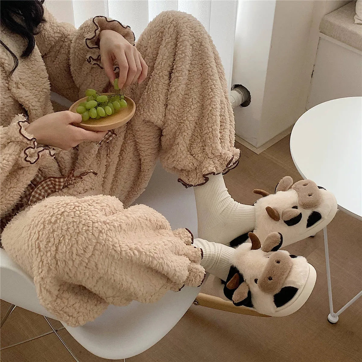 White women's cow pattern slippers made of soft faux fur with textured anti-slip soles.