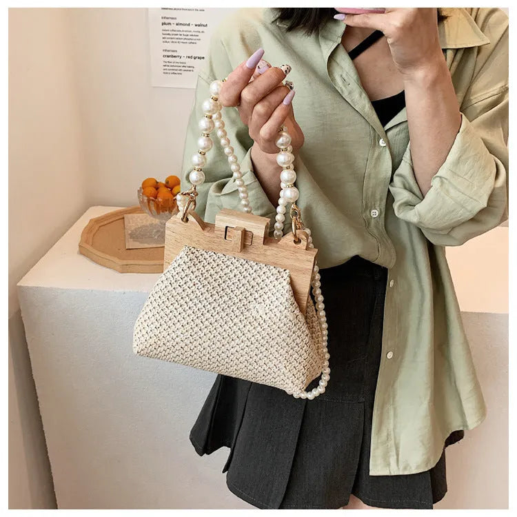 Women's woven straw shoulder bag with pearl chain strap in beige, showing internal organiser pockets.