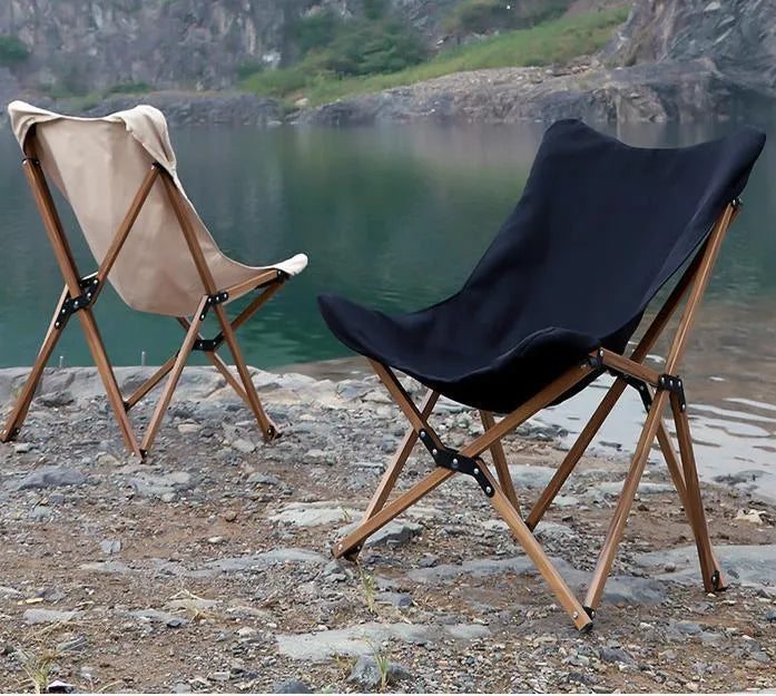 Folding camping chair with aluminium frame, wood grain finish, handrails, and rotating seat in outdoor setting