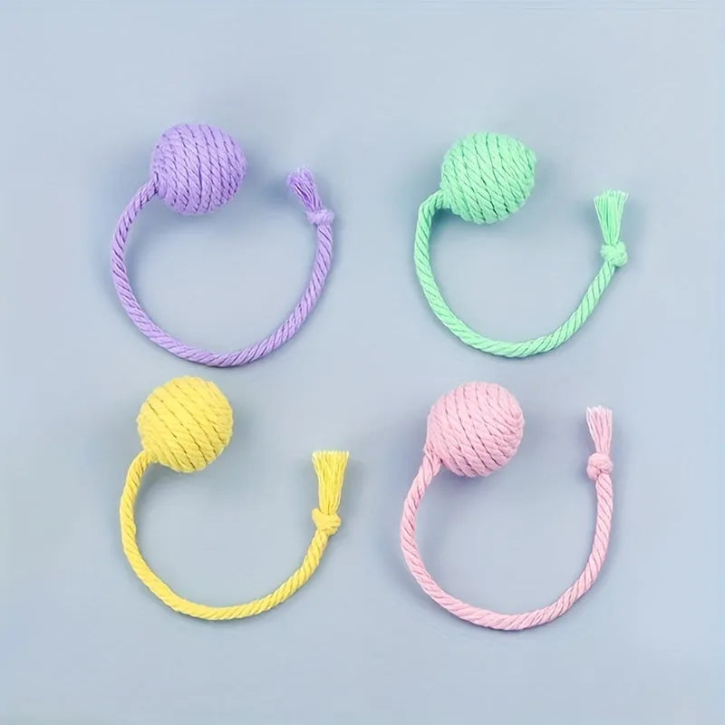 Colourful cat toy ball with attached rope and internal bell, shown in green, pink, purple, and yellow variants.