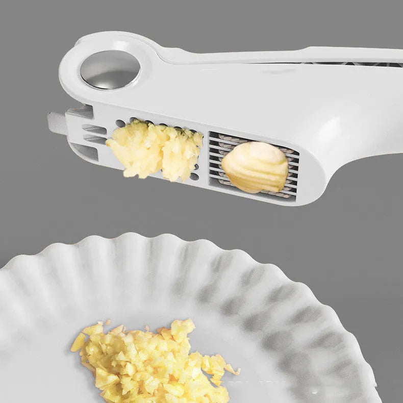 White manual garlic press with stainless steel crusher on a kitchen worktop.