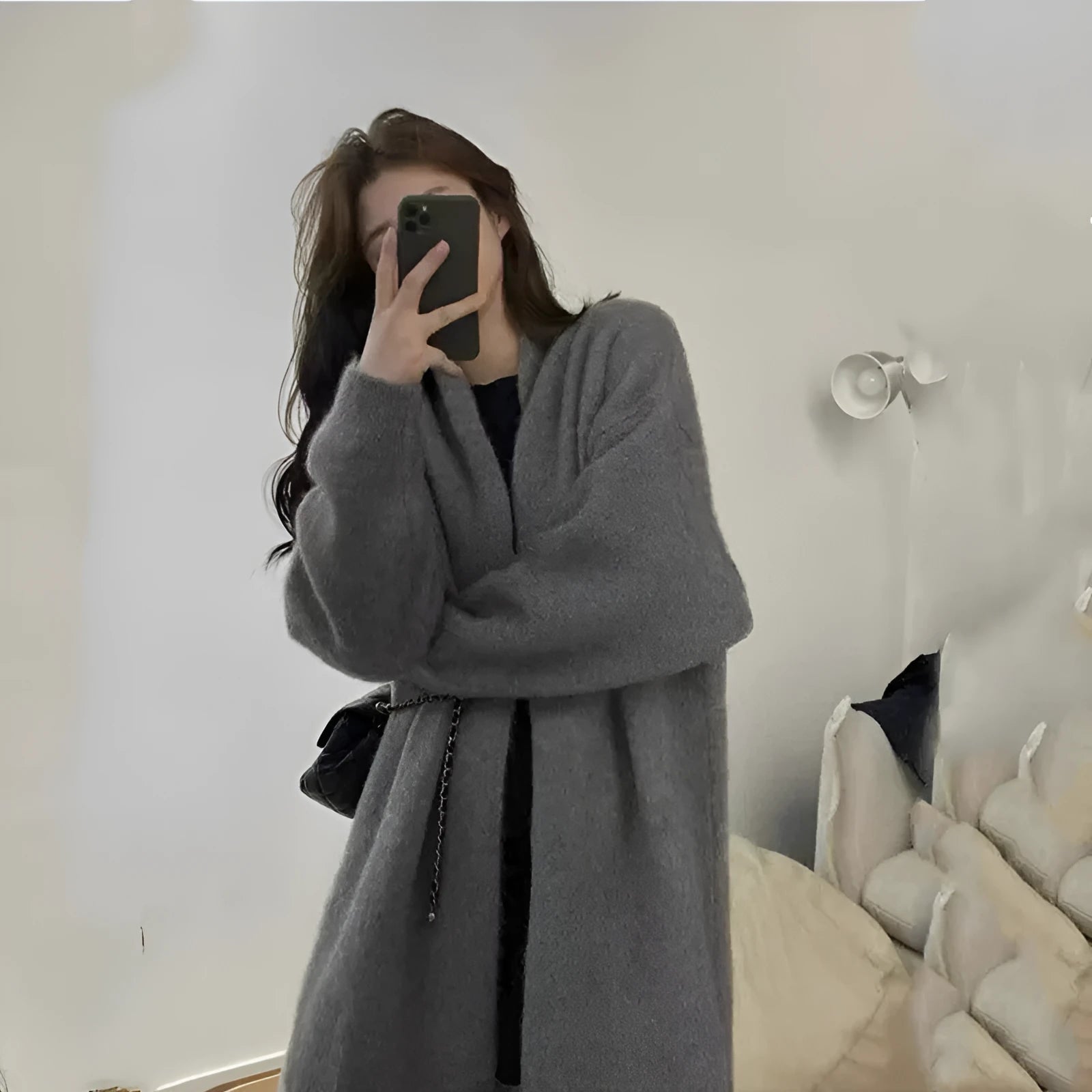 Loose large dark grey knitted cardigan with a 3D pattern, worn open over a top.