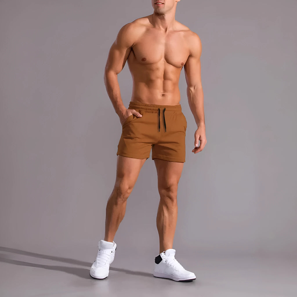 Three pairs of men's solid-colour drawstring shorts in black, khaki, and light brown laid flat.
