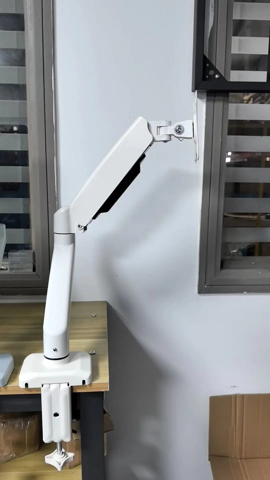 Black metal LCD screen rotating telescopic bracket elevated on desktop with adjustable angle
