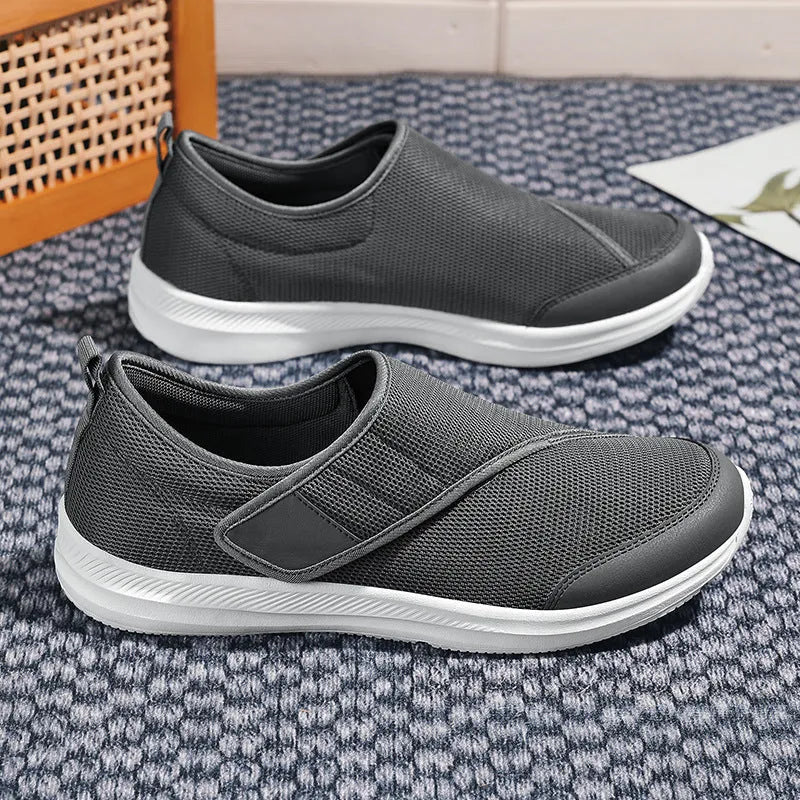 A pair of grey mesh walking shoes with a Velcro strap closure, shown on a white background.