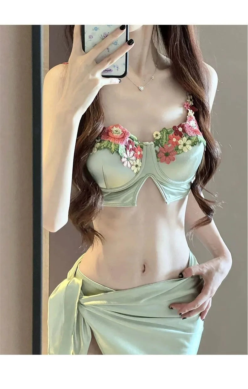Green women's three-piece bikini set with triangle top, briefs, and skirt on white background